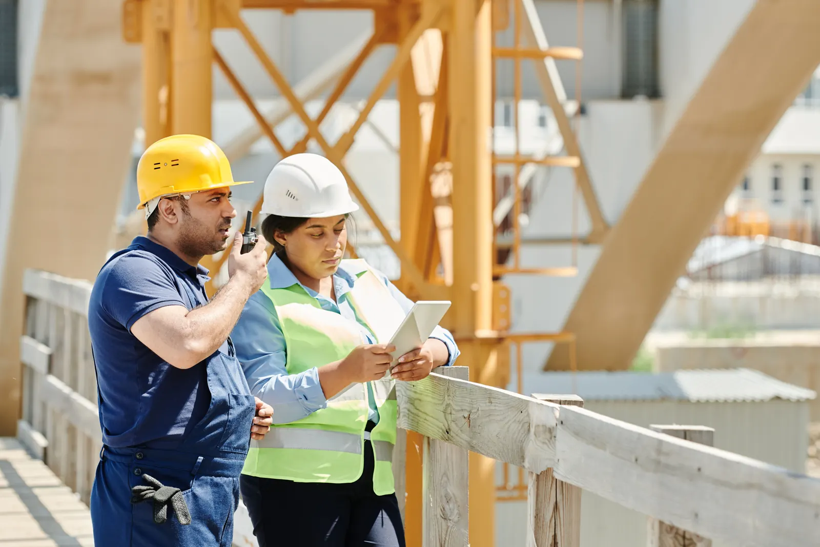 Supervisor con radio e ingeniera con tablet haciendo una inspección en obra