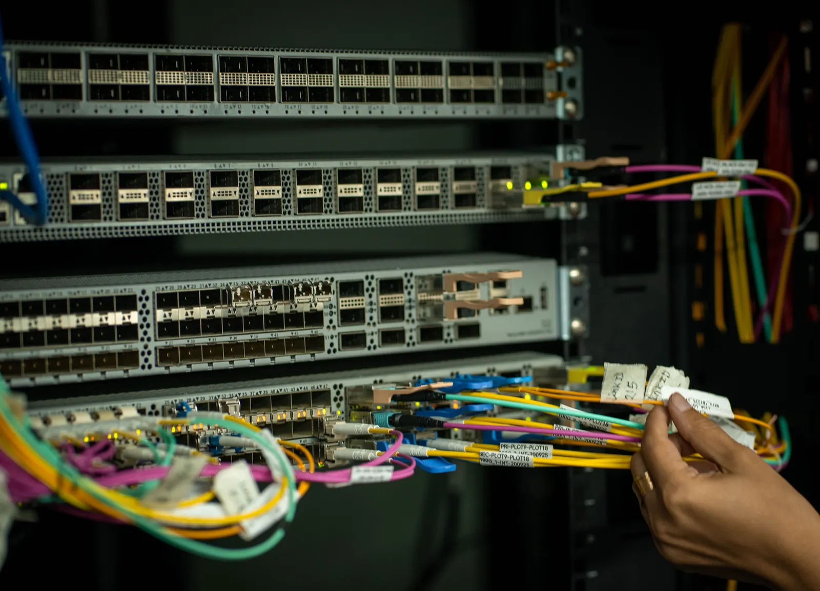 Técnico conectando cables de fibra óptica en un rack de comunicaciones